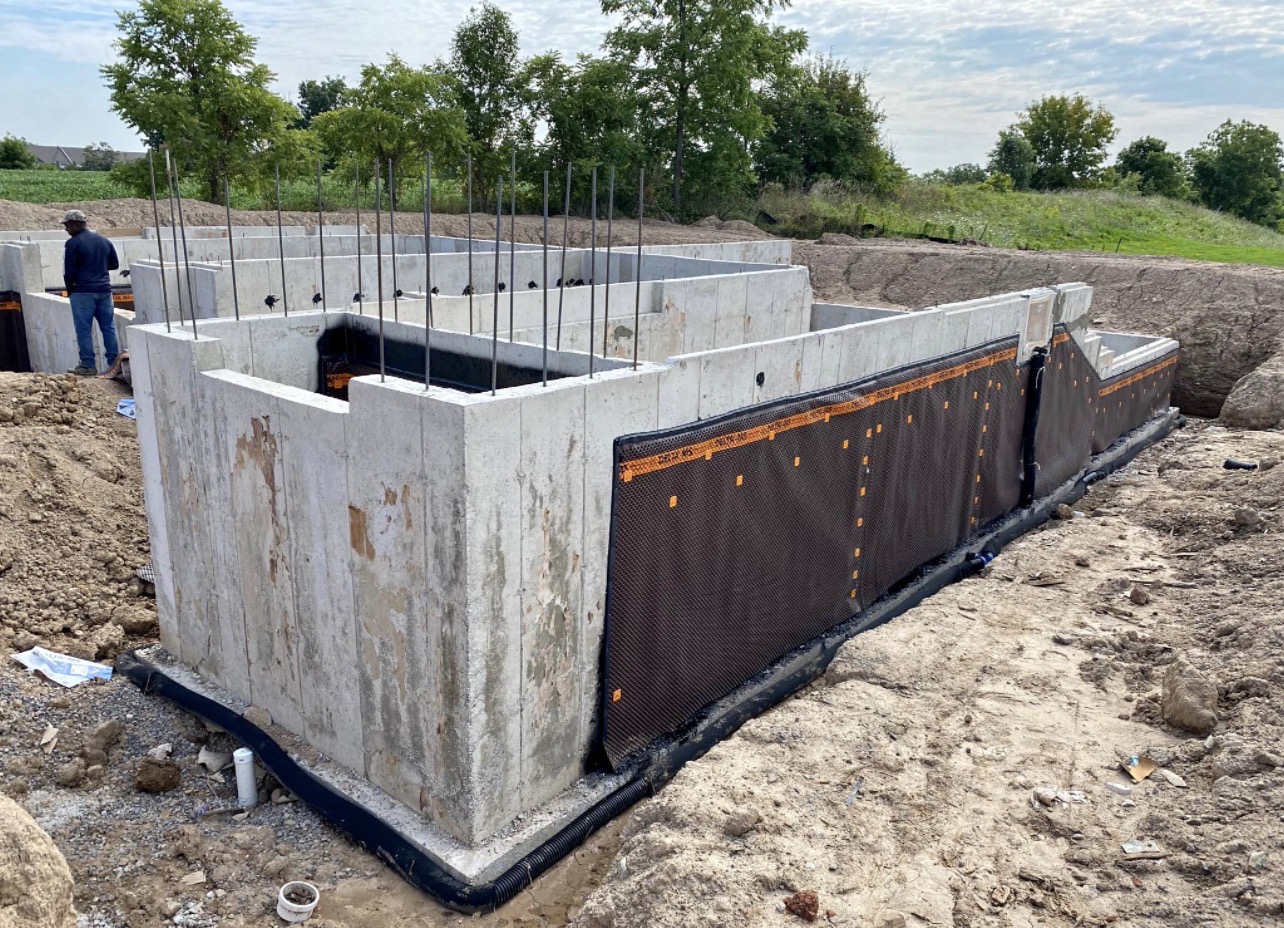 Newly poured concrete foundation walls with drainage protection on a TradeFill site